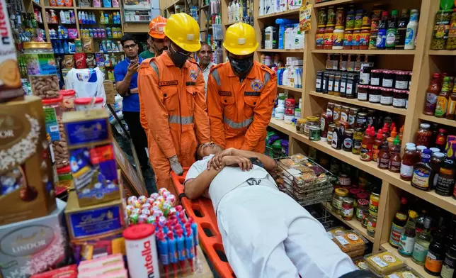 National Disaster Response Force team members carry out a mock drill in a market to train civilians and security personnel to respond in case of attack, in New Delhi, India, Wednesday, May 7, 2025. (AP Photo/Manish Swarup)