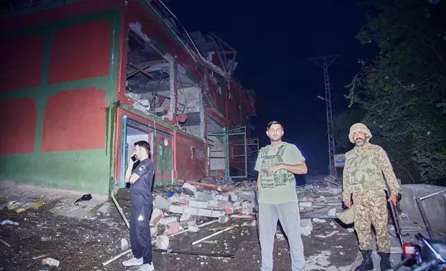 Security force officials stand outside a damaged building at a site of a suspected Indian missile attack near Muzaffarabad, the capital of Pakistan controlled Kashmir, in Wednesday, May 7, 2025. (AP Photo/M.D. Mughal)