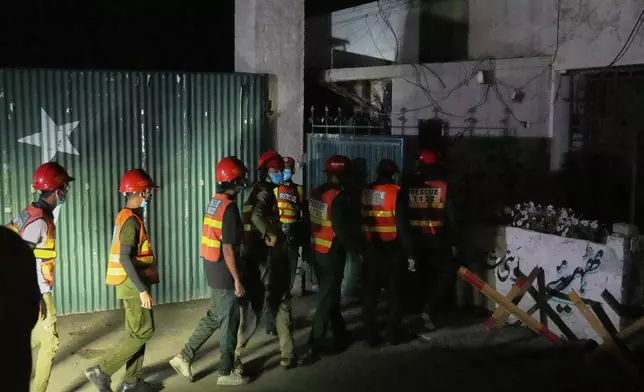Rescue workers enter a building near the site of a suspected Indian missile attack, in Muridke, a town in Pakistan's Punjab province, Wednesday, May 7, 2025. (AP Photo/K.M. Chaudary)