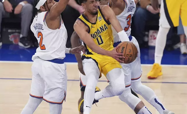Indiana Pacers guard Tyrese Haliburton (0) goes up for a shot against New York Knicks guard Miles McBride (2) and guard Josh Hart (3) during the second quarter of Game 2 of the NBA basketball Eastern Conference final, Friday, May 23, 2025, in New York. (AP Photo/Frank Franklin II)
