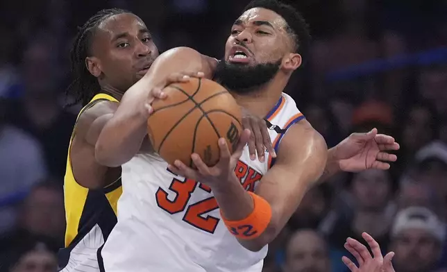 New York Knicks center Karl-Anthony Towns (32) gets tangled up with Indiana Pacers forward Aaron Nesmith (23) during the third quarter of Game 2 of the NBA basketball Eastern Conference final, Friday, May 23, 2025, in New York. (AP Photo/Frank Franklin II)