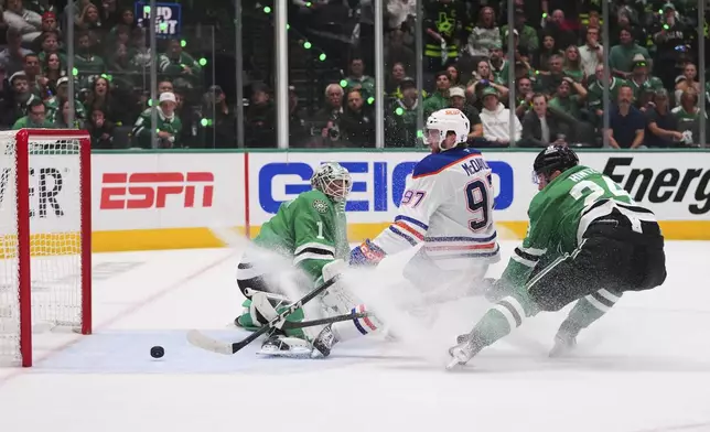 Edmonton Oilers center Connor McDavid (97) scores against Dallas Stars goaltender Casey DeSmith (1) and center Roope Hintz (24) during the second period of Game 5 of the Western Conference finals in the NHL hockey Stanley Cup playoffs, Thursday, May 29, 2025, in Dallas. (AP Photo/Julio Cortez)