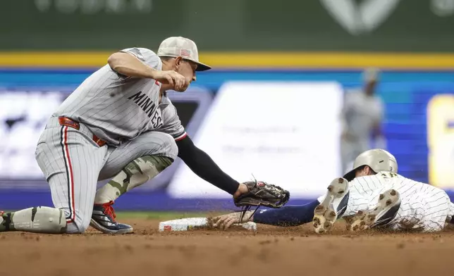 Milwaukee Brewers' Brice Turang, right, safely steals second base as Minnesota Twins' Brooks Lee makes a late tag during the first inning of a baseball game, Friday, May 16, 2025, in Milwaukee. (AP Photo/Jeffrey Phelps)