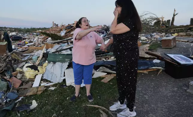 Bea Johnson, left, reaches for her sister Kristie Sexton, right, as she reacts standing next to her destroyed home after a severe storm passed through the area, Saturday, May 17, 2025, in London, Ky. (AP Photo/Carolyn Kaster)