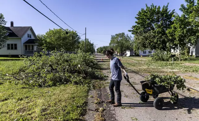Zeeland resident Maddie Pellegrini clears debris outside her family's home on 64th Avenue in Drenthe east of Zeeland, Mich. on Friday, May 16, 2025. (Isaac Ritchey/The Grand Rapids Press via AP)
