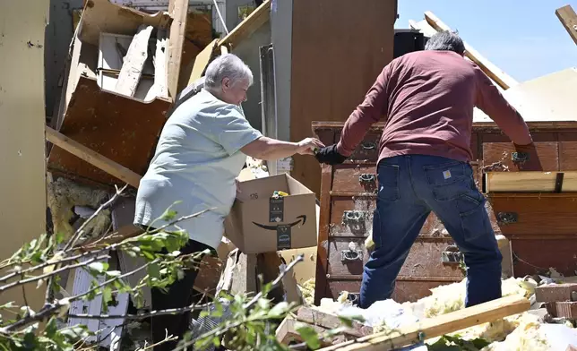 Don Allen, right, hands Doris Hensley medication that they are retrieving from the remains of her home following severe weather last night in London, Ky., Saturday, May 17, 2025. (AP Photo/Timothy D. Easley)