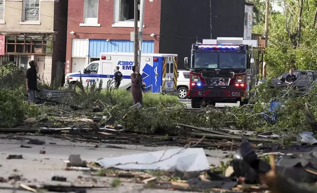 People survey damage after a severe storm moved through Friday, May 16, 2025, in St. Louis. (AP Photo/Jeff Roberson)