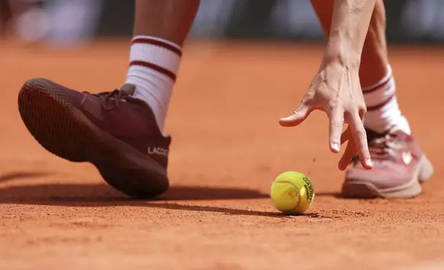 A ball boy reaches for a ball during the first round match of the French Tennis Open between Poland's Iga Swiatek and Slovakia's Rebecca Sramkova, at the Roland-Garros stadium, in Paris, Monday, May 26, 2025. (AP Photo/Lindsey Wasson)