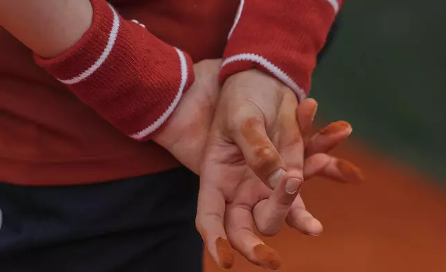 Clay lies on the hands of ball boy standing by a court during a first round match of the French Tennis Open, at the Roland-Garros stadium, in Paris, Tuesday, May 27, 2025. (AP Photo/Aurelien Morissard)
