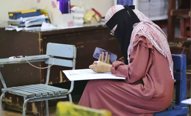 A woman casts her ballot at a polling station set up at a school in Davao City, southern Philippines, Monday, May 12, 2025. (AP Photo/Manman Dejeto)