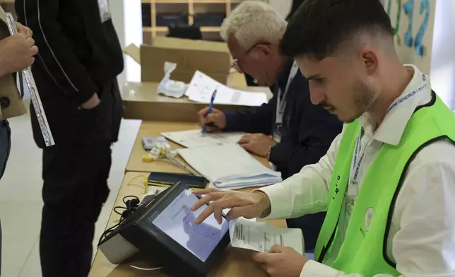 A man checks documents during a general election in Tirana, Albania Sunday, May 11, 2025. (AP Photo/Vlasov Sulaj)