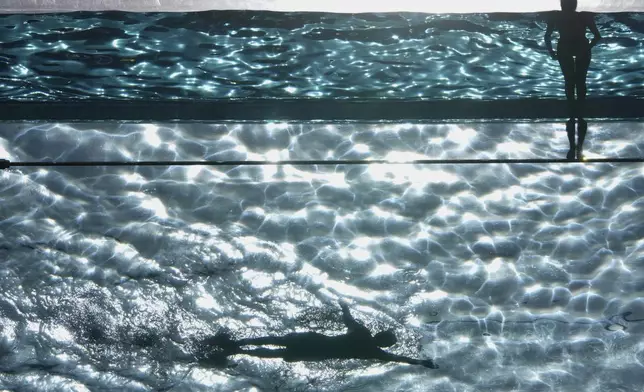 People swim in the Sky Pool on a sunny day in London, Thursday, May 1, 2025. (AP Photo/Kin Cheung)