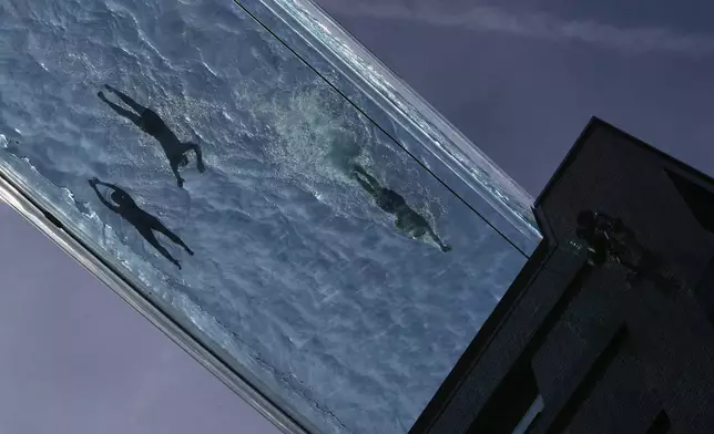 People swim in the Sky Pool on a sunny day in London, Thursday, May 1, 2025. (AP Photo/Kin Cheung)