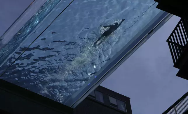 A man swims in the Sky Pool on a sunny day in London, Thursday, May 1, 2025. (AP Photo/Kin Cheung)