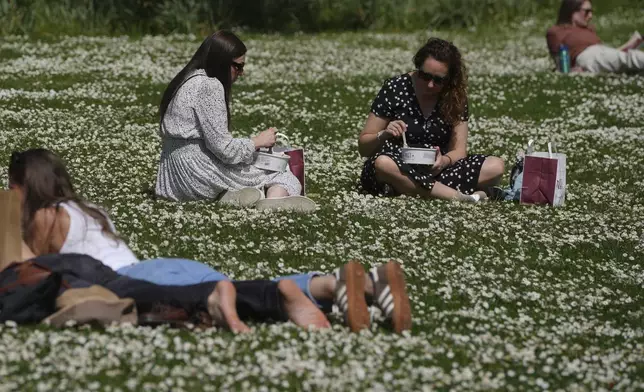 People have lunch on a sunny day at a park in London, Wednesday, April 30, 2025. (AP Photo/Kin Cheung)