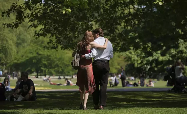A couple walk on a sunny day at a park in London, Wednesday, April 30, 2025. (AP Photo/Kin Cheung)