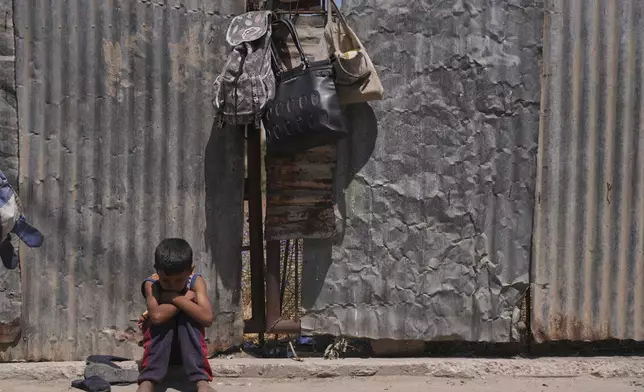 A Palestinian boy sits on the curb as he waits near a food distribution kitchen in Deir al-Balah, Gaza Strip, Friday, May 30, 2025. (AP Photo/Abdel Kareem Hana)