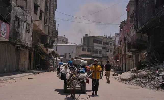 Smoke rises to the sky following an Israeli airstrike as Palestinians fleeing Jabaliya move with their belongings in Gaza City, Friday, May 30, 2025. (AP Photo/Jehad Alshrafi)