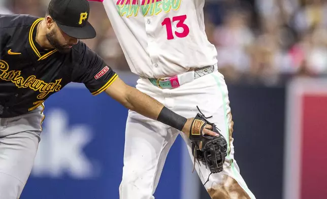 San Diego Padres third baseman Manny Machado (13) signals that he should be safe at second base after sliding past Pittsburgh Pirates shortstop Isiah Kiner-Falefa, left, in the fourth inning of a baseball game, Friday, May 30, 2025, in San Diego. (AP Photo/Tony Ding)