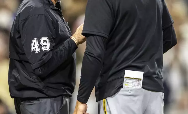Umpire Andy Fletcher (49) talks with Pittsburgh Pirates manager Don Kelly, right, after the eighth inning of a baseball game against the San Diego Padres, Friday, May 30, 2025, in San Diego. (AP Photo/Tony Ding)