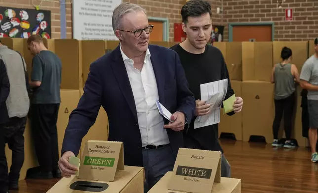 Australian Prime Minister Anthony Albanese and his son Nathan place their votes in a ballot box at a polling booth in his electorate in Sydney, Saturday, May 3, 2025. (AP Photo/Rick Rycroft)