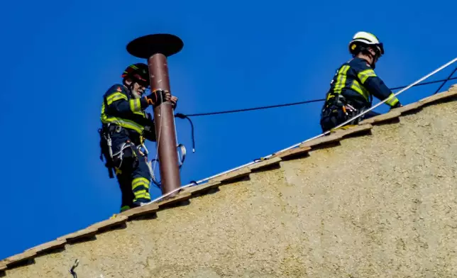 Firefighters place the chimney on the roof of the Sistine Chapel, where cardinals will gather to elect the new pope, at the Vatican, Friday, May 2, 2025. (AP Photo/Gregorio Borgia)