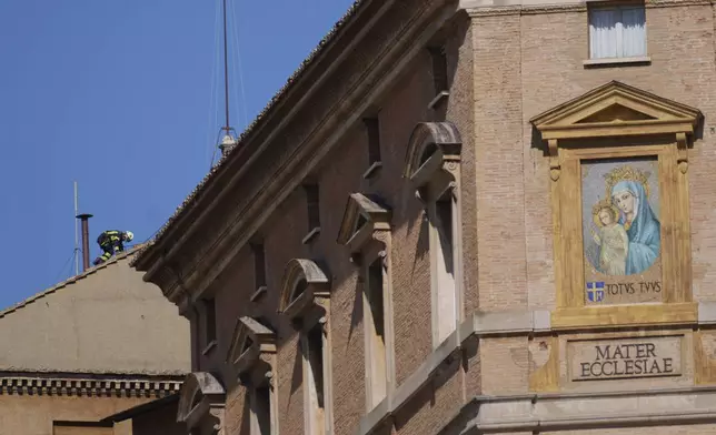Firefighters place the chimney on the roof of the Sistine Chapel, where cardinals will gather to elect the new pope, at the Vatican, Friday, May 2, 2025. (AP Photo/Gregorio Borgia)