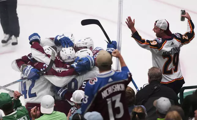 Colorado Avalanche's Nathan MacKinnon (29), is congrulated by the line after scoring against the Dallas Stars in the third period in Game 7 of a first-round NHL hockey playoff series Saturday, May 3, 2025, in Dallas. (AP Photo/Julio Cortez)