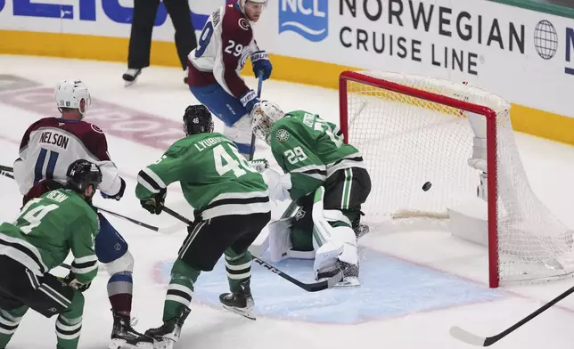 Colorado Avalanche's Nathan MacKinnon (29) sores against Dallas Stars' Jake Oettinger (29) as Brock Nelson (11), Dallas Stars' Jamie Benn (14) and Ilya Lyubushkin (46) look on in the third period in Game 7 of a first-round NHL hockey playoff series Saturday, May 3, 2025, in Dallas. (AP Photo/Julio Cortez)
