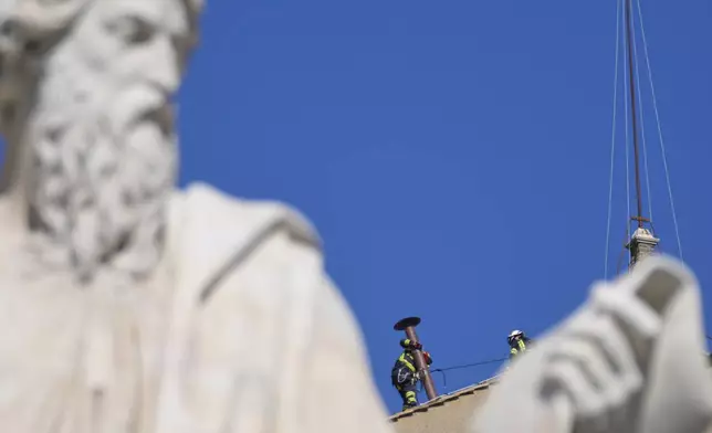 Firefighters place the chimney on the roof of the Sistine Chapel, where cardinals will gather to elect the new pope, at the Vatican, Friday, May 2, 2025. (AP Photo/Gregorio Borgia)