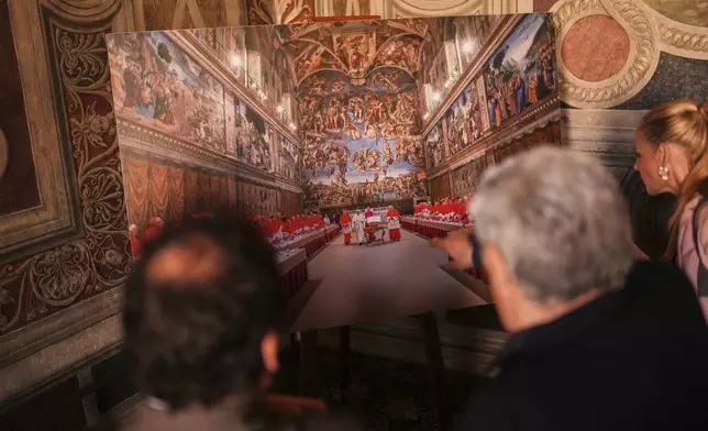 Journalists look at a photograph of the conclave where late Pope Francis was elected on March 13, 2013, and displayed inside the Borgia Apartments at the Vatican Museums during a press tour, Friday, May 2, 2025. (AP Photo/Francisco Seco)