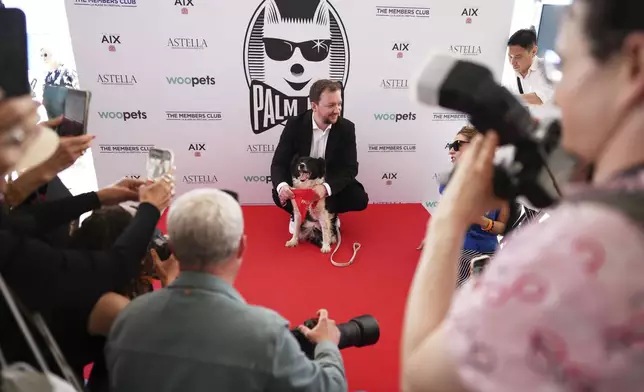 Anthony Provost, centre, and Perle pose for photographers after receiving the Palm Dog award on behalf of Panda, who could not attend, during the Palm Dog award ceremony at the 78th international film festival in Cannes, southern France, Friday, May 23, 2025. (AP Photo/Natacha Pisarenko)