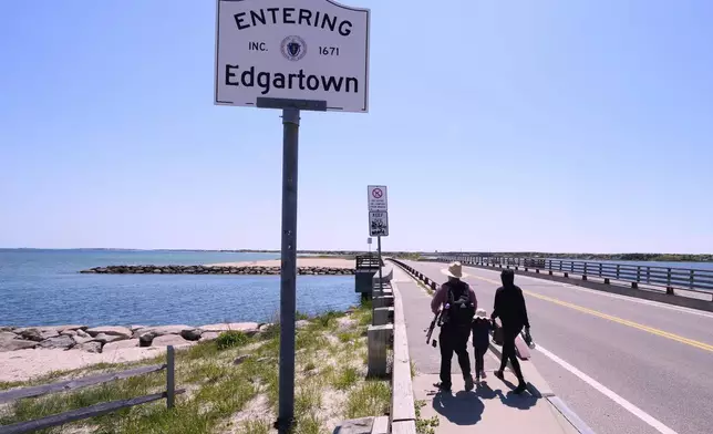 A family walks to the span of the American Legion Memorial Bridge, also known as the "Jaws Bridge", while spending the day fishing, Monday, May 12, 2025, in Edgartown, Mass., on Martha's Vineyard Island. (AP Photo/Charles Krupa)