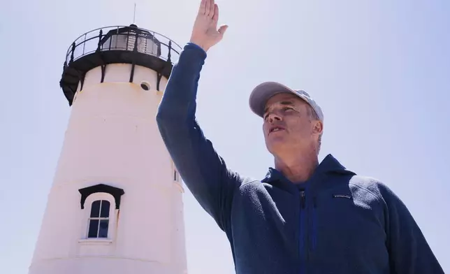 Endurance swimmer Lewis Pugh gestures to where he will begin his swim around Martha's Vineyard island, which is expected to take 12 days, near the Edgartown Lighthouse, Monday, May 12, 2025, in Edgartown, Mass. (AP Photo/Charles Krupa)