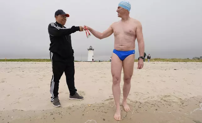 Endurance swimmer Louis Pugh fist bumps a beach-goer before entering the water to begin his swim around Martha's Vineyard, Thursday, May 15, 2025, in Edgartown, Mass. (AP Photo/Robert F. Bukaty)