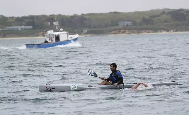 Kayaker Nicholas Burden guides endurance swimmer Louis Pugh as a fishing boat passes by, Thursday, May 15, 2025, off Edgartown, Mass. (AP Photo/Robert F. Bukaty)