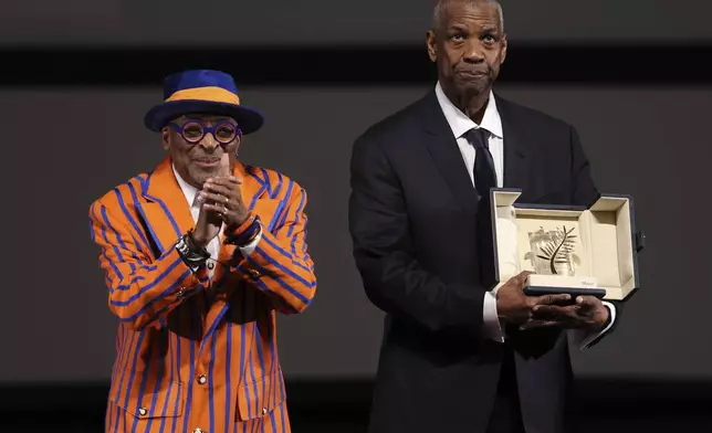 Actor Denzel Washington receives an Honorary Palme d'Or (Golden Palm) from director Spike Lee, left, ahead of the screening of the film "Highest 2 Lowest" at the 78th edition of the Cannes Film Festival in Cannes, southern France, Monday, May 19, 2025. (Sameer Al-Doumy, Pool via AP)