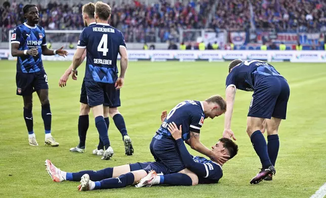 Heidenheim's goalscorer Mathias Honsak, below, celebrates with his teammates after scoring a goal in a soccer match against Elversberg in the Bundesliga promotion-relegation playoff in Spiesen-Elversberg, Germany, Monday, May 26, 2025. (Uwe Anspach/dpa via AP)