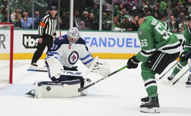 Winnipeg Jets goaltender Connor Hellebuyck (37) defends against a shot by Dallas Stars' Thomas Harley (55) in the third period of Game 3 of a second-round NHL hockey playoff series in Dallas, Sunday, May 11, 2025. (AP Photo/Julio Cortez)