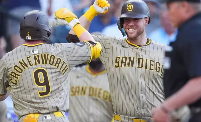 San Diego Padres' Gavin Sheets, right, congratulates Jake Cronenworth who returns to the dugout after hitting a solo home urn off Colorado Rockies starting pitcher Bradley Blalock in the third inning of a baseball game Saturday, May 10, 2025, in Denver. (AP Photo/David Zalubowski)