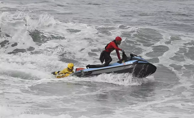 CORRECTS DAY: Lifeguards look for survivors after a boat capsized in the surf Monday, May. 5, 2025, in at Torrey Pines State beach in San Diego, Calif. (AP Photo/Denis Poroy)