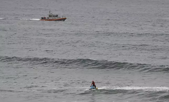 CORRECTS DAY: A U.S Coast Guard boat and lifeguards look for survivors after a boat capsized in the surf Monday, May. 5, 2025, in at Torrey Pines State beach in San Diego, Calif. (AP Photo/Denis Poroy)