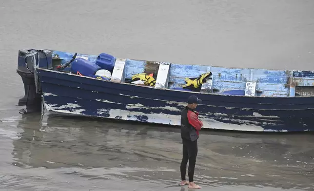 CORRECTS DAY: A Del Mar lifeguard looks over a capsized boat on the beach Monay, May. 5, 2025, in at Torrey Pines State beach in San Diego, Calif. (AP Photo/Denis Poroy)