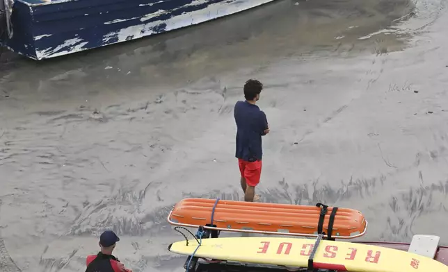Del Mar lifeguards looks over a capsized boat on the beach Monday, May. 5, 2025, in at Torrey Pines State beach in San Diego, Calif. (AP Photo/Denis Poroy)
