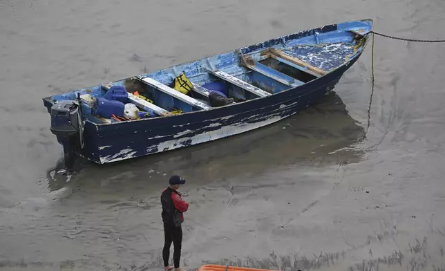 Del Mar lifeguards looks over a capsized boat on the beach Monday, May 5, 2025, in at Torrey Pines State beach in San Diego, Calif. (AP Photo/Denis Poroy)