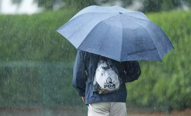 A volunteer walk the course in the rain during a practice round for the PGA Championship golf tournament at the Quail Hollow Club, Monday, May 12, 2025, in Charlotte, N.C. (AP Photo/Matt York)