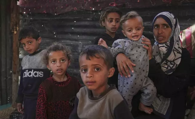 Wedad Abdelaal, right, and her 9-month-old son Khaled who is suffers from malnutrition and her children Ahmed, 7 and Maria, 4, both showing signs of malnutrition also, pose for a photo in their tent at a camp for displaced Palestinians in Mawasi, Khan Younis, Gaza Strip, Friday, May 2, 2025. (AP Photo/Abdel Kareem Hana)