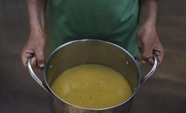 A Palestinian child carries a pot of soup received from a community kitchen in Khan Younis, Gaza Strip, on Saturday, May 3, 2025. (AP Photo/Abdel Kareem Hana)