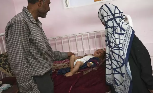 Wedad Abdelaal, right, and her husband Ammar care for their 9-month-old son Khaled, at the malnutrition clinic in Nasser hospital, Khan Younis, Gaza Strip, Thursday, May 1, 2025. (AP Photo/Abdel Kareem Hana)