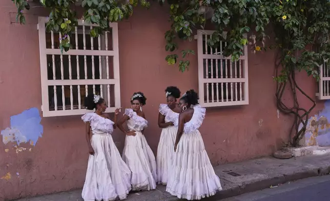Dancers gather on a sidewalk after performing at a wedding in Cartagena, Colombia, Saturday, May 10, 2025. (AP Photo/Rodrigo Abd)